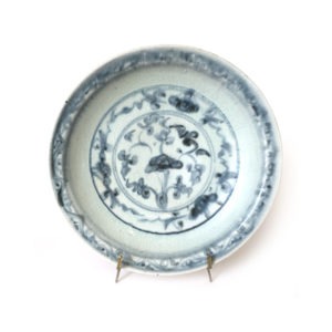 Plat en porcelaine bleu et blanc décor de végétaux sous couverte.